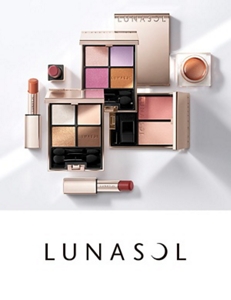 Two opened Lunasol makeup palette cases, one containing darker shades and one lighter, atop correlating powders in the background. 