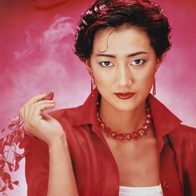  A “Lady 80” campaign advertisement from the 1980s featuring a woman wearing a red shirt and red jewelry looking directly into the camera. 