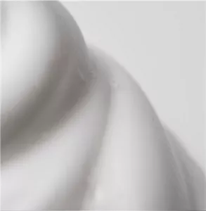 Nahaufnahme einer weißen, mousseartigen Form auf weißem Hintergrund.