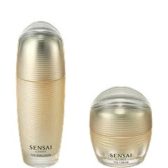 Ultimative Emulsion in einem goldenen Glasflakon und Creme in einem goldenen Tiegel vor schwarzem Hintergrund