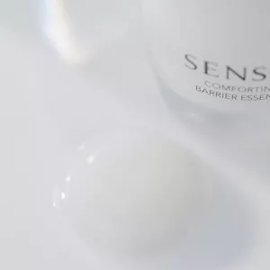 Gros plan de la texture Comforting Barrier Essence de SENSAI à côté du tube de produit