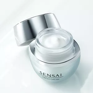 Il vasetto aperto del prodotto Cellular Performance Fresh Cream di SENSAI mostra la consistenza su uno sfondo bianco testurizzato