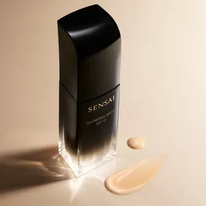 Glowing Base product bottle next swab of texture on neutral surface with mood lighting