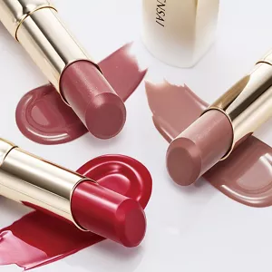 Tre Moisture Intense Lipstick in oro con stick esposti e texture cremosa corrispondente (rosso intenso, malva rosato, nude rosa) su una superficie bianca