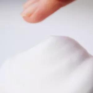 指尖轻触蓬松白色泡沫的特写