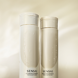 Volumising Shampoo and Smoothing Shampoo bottles in front of a beige background