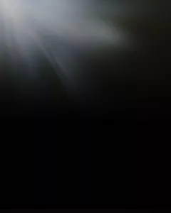Ein Lichtstrahl leuchtet von der linken oberen Ecke auf einen dunklen Hintergrund