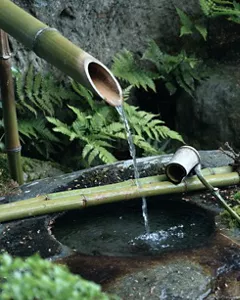 Un filo d’acqua scorre da una fontana in bambù in un ruscello.