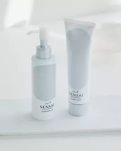Un tubetto bianco di detergente e un flacone con erogatore su sfondo bianco.