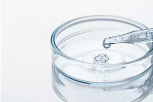 Gros plan d’une pipette déversant une goutte de liquide dans un récipient.