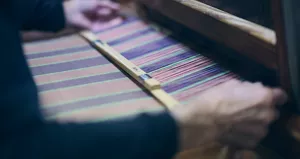 Gros plan d’une personne tissant du textile sur un métier à tisser.