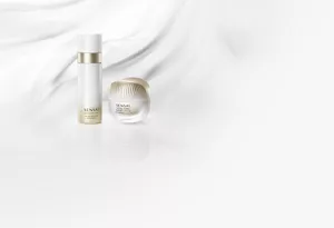 Absolute Silk Micro Mousse Treatment and Total Form Expert Cream, gold-and-white bottle and jar on flowing white texture