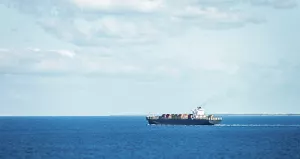 貨物を積んだ貨物船が、穏やかな海を航行している景色。