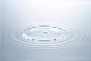 水面に雫が落ちて波紋が広がるイメージ。
