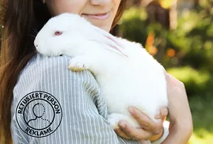 En modell klemmer sjenerøst om en hvit kanin.