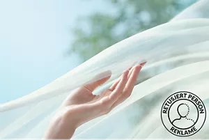 Venstre håndflate berører et halvgjennomsiktig hvitt slør som flyter i luften.