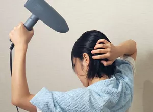 耳の後ろの髪を手で持ち上げ、根元にドライヤーの風を当てる画像