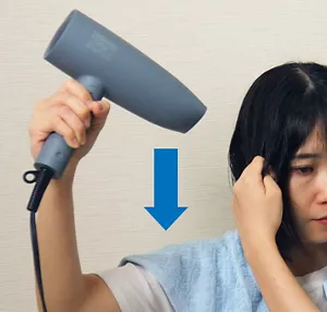 ドライヤーを上から下に向けて、毛先まで温風を当てる画像