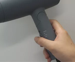ドライヤーを冷風に切り替えて持っている画像