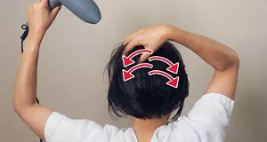 つむじ周りの髪を指でいろいろな方向に動かしながら、ドライヤーの風を当てる画像