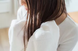 長い髪をタオルで包み、手のひらでやさしくたたいて毛先の水分を吸い取る画像
