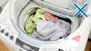 写真：悪い事例　洗濯槽からはみ出るほど洗濯物が入った洗濯機