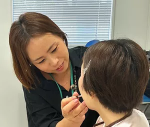 着席している女性にメイクをする岩谷の写真