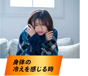 身体の冷えを感じる時。部屋でブランケットにくるまって、寒そうにうずくまっている女性イメージ