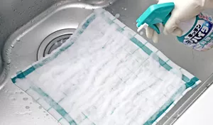 シンクに広げたふきんにキッチン泡ハイターをスプレーしている写真。