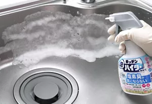 シンクに向かってキッチン泡ハイター無臭性タイプをスプレーしている写真。