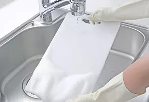 まな板にスプレーされたキッチン泡ハイターの泡を洗い流している写真。流し終えた箇所はきれいに漂白されている。