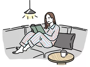 ソファに座って読書を楽しむパジャマ姿の女性のイラストイメージ