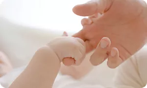 ママの指を握る新生児