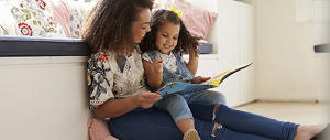 A young mother reading a book to her toddler.