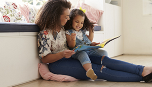A young mother reading a book to her toddler.
