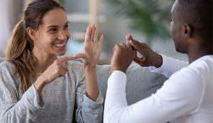 A young woman and man speaking in sign language.