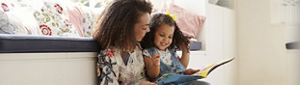 A young mother reading a book to her toddler.