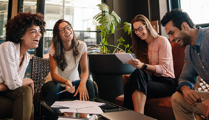 Four young, diverse co-workers in a modern environment laughing.