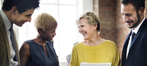 Four diverse co-workers of varying ages smiling at one another.
