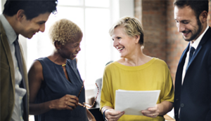 Four diverse co-workers of varying ages smiling at one another.