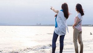 Two women on a beach looking out over the water