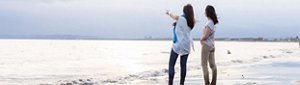 Two women on a beach looking out over the water
