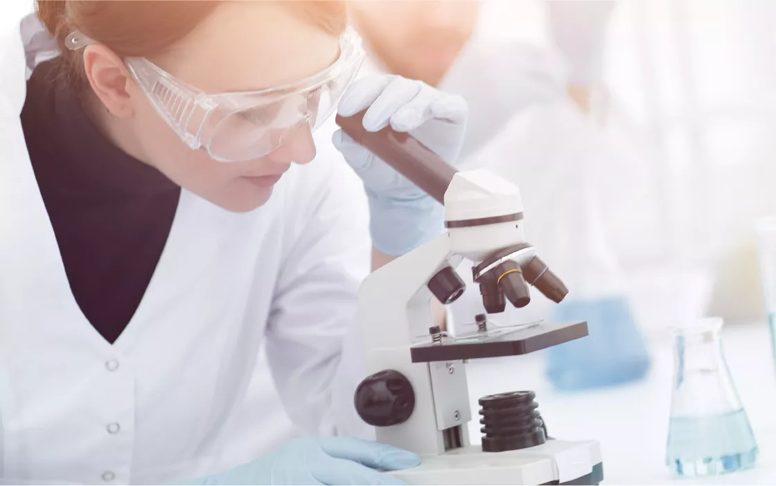 A photo of a woman looking through a microscope