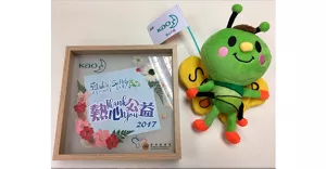 一個經過裝裱的感謝狀和一隻毛絨蝴蝶公仔，公仔身後掛著印有花王標誌的旗幟。