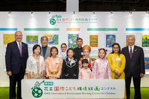 第9屆比賽的得獎者和評委站在花王國際兒童環境繪畫比賽的橫額後面合照。他們身後展示了各個參賽作品。
