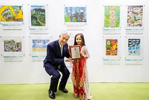 一個身穿紅色民族服裝的小女孩從時任花王株式會社總裁兼執行長澤田道隆先生手上接過獎狀。