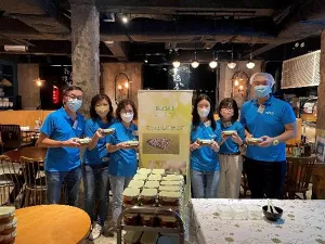 6名義工拿著飯盒合照。他們中間擺放著一輛裝滿飯盒的廚房手推車。