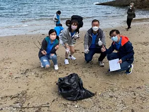 4名花王香港員工分別拿著收集垃圾的工具和紀錄板在海灘上合照。