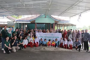 image of participants taking a group photo and holding a banner at the PHBS education activity with clean water in Girimulyo, Yogyakarta
