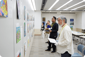 複数の審査員がこどもたちの作品を見ながら審査している様子
